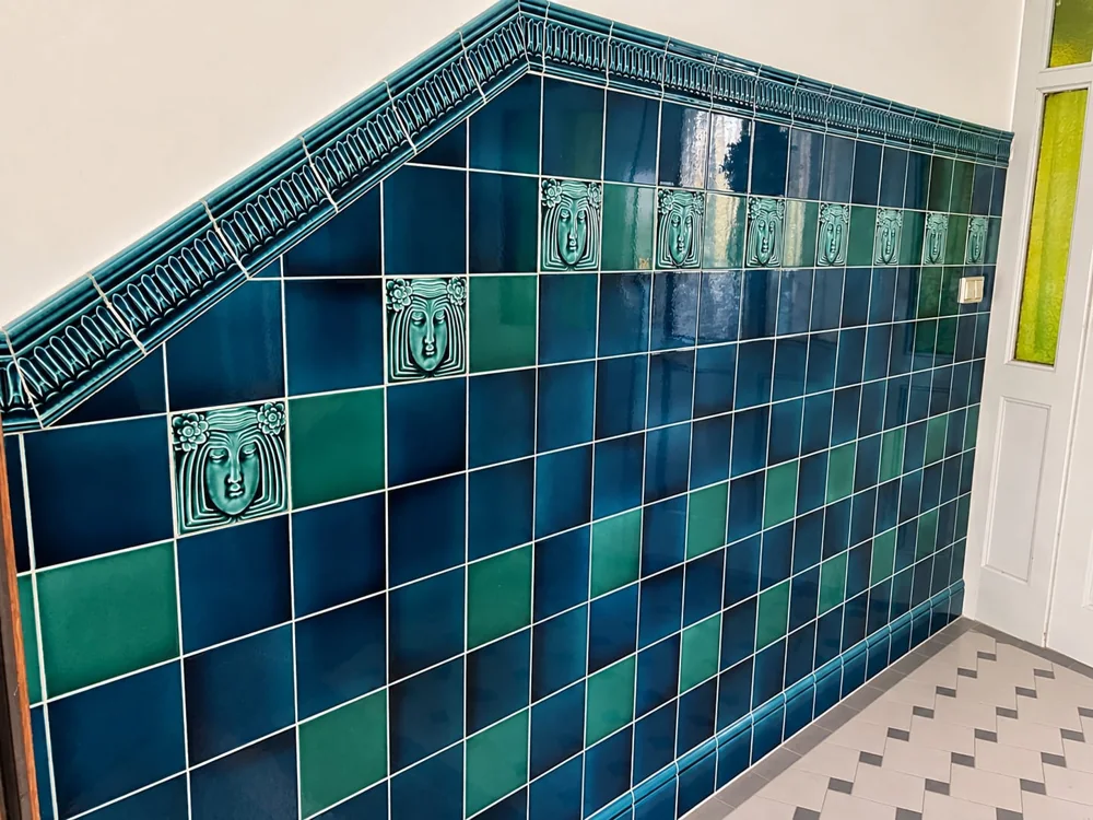 Glasierte blau-grüne Wandfliesen mit dekorativer Bordüre.